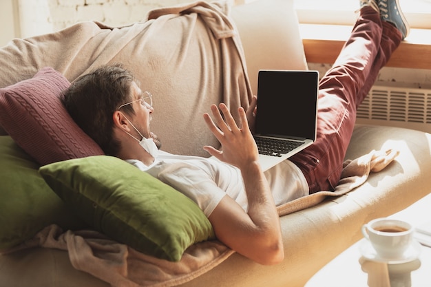 Giovane che studia a casa durante i corsi online per giornalisti, critici, scrittori. Ottenere la professione mentre si è isolati, mettere in quarantena contro la diffusione del coronavirus. Utilizzando laptop, smartphone, cuffie.