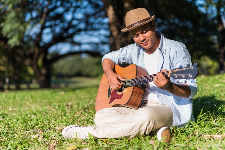 Foto giovane che suona la chitarra sull'erba