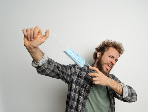 Giovane che tiene la mascherina medica protettiva davanti alla faccia pronta per terminare la quarantena