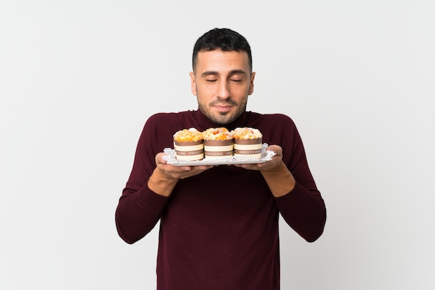 Giovane che tiene le mini torte che godono dell'odore di loro