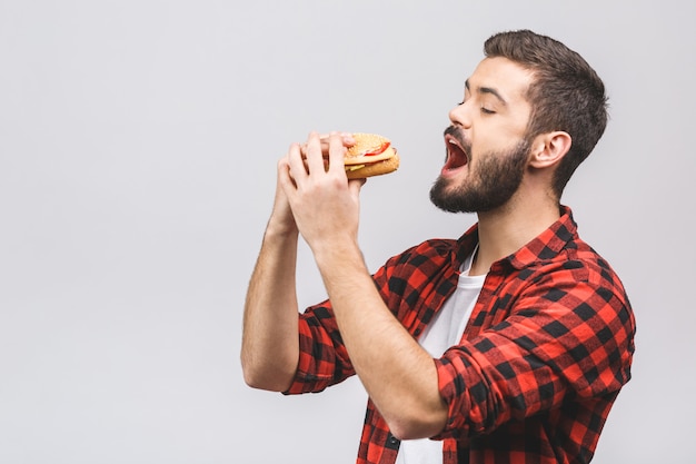 Giovane che tiene un pezzo di hamburger. Concetto di dieta isolato su sfondo bianco.