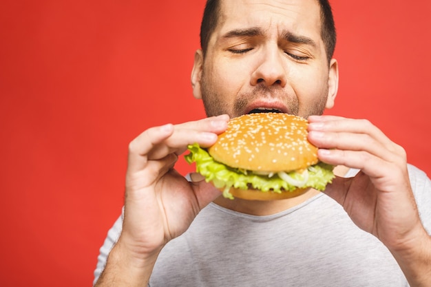 Giovane che tiene un pezzo di hamburger.