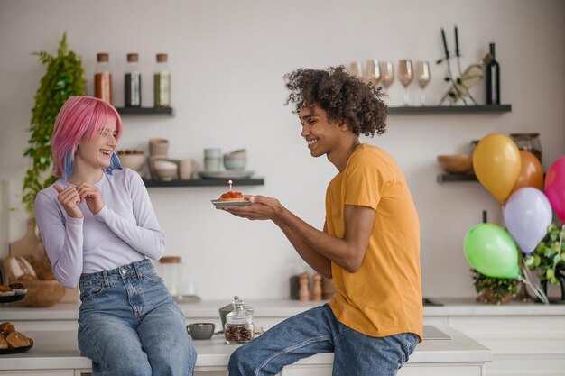 Giovane che tiene una torta di fragole con una candela la sua ragazza felice