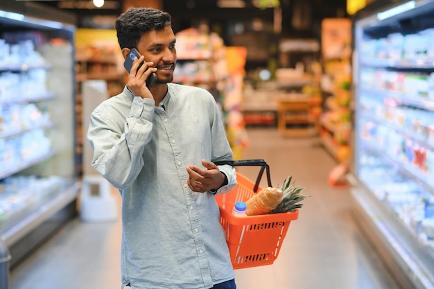 Giovane che usa il cellulare mentre fa la spesa al supermercato