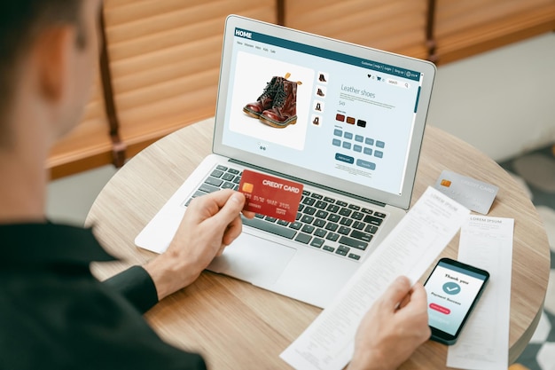 Giovane che usa il portatile con la carta di credito per l'internet banking