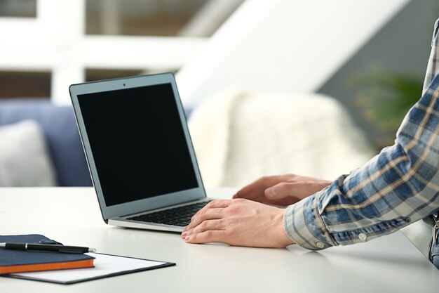Giovane che usa un laptop moderno a tavola