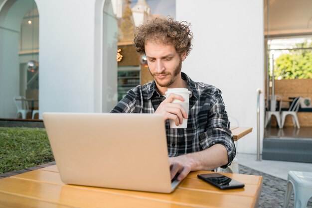 Giovane che utilizza il suo computer portatile in una caffetteria