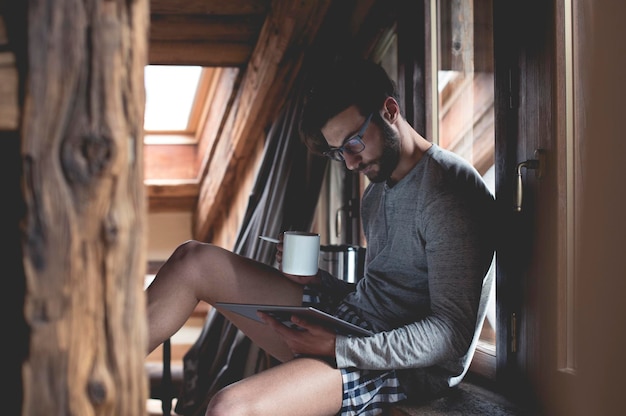 Giovane che utilizza tablet e beve caffè a casa