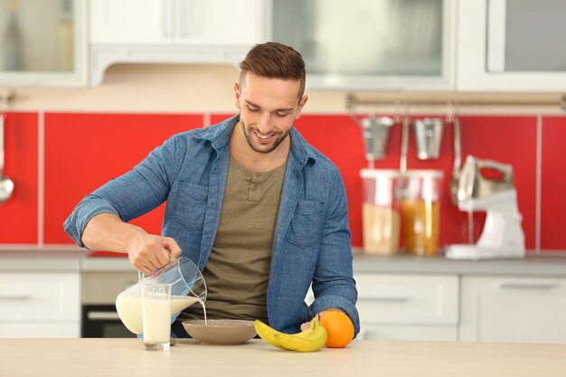 Giovane che versa il latte fresco nella ciotola in cucina