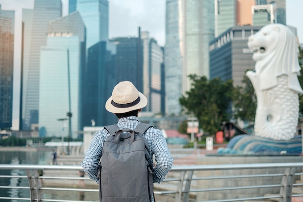 Giovane che viaggia con lo zaino e il cappello di mattina, visita asiatica sola del viaggiatore nella città di Singapore del centro. punto di riferimento e popolare per le attrazioni turistiche. Concetto di viaggio in Asia