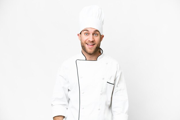 Giovane chef biondo su sfondo bianco isolato con espressione facciale a sorpresa