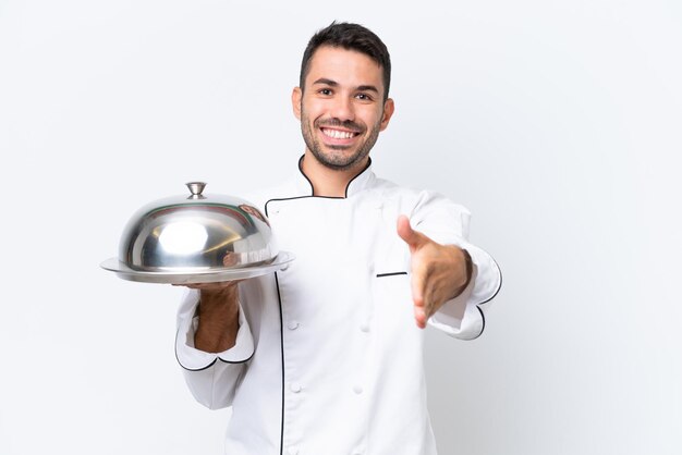 Giovane chef con vassoio isolato su sfondo bianco si stringono la mano per chiudere un buon affare