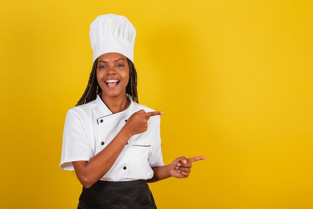 Giovane chef donna afrobrasiliana che presenta qualcosa a destra indicando qualcosa