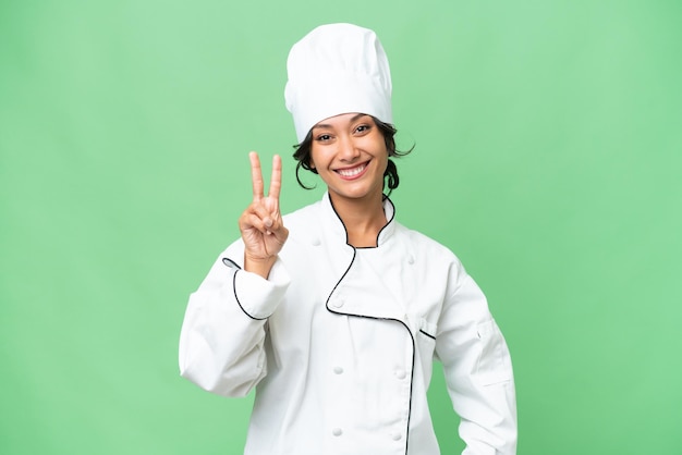 Giovane chef donna argentina su sfondo isolato sorridente e mostrando segno di vittoria