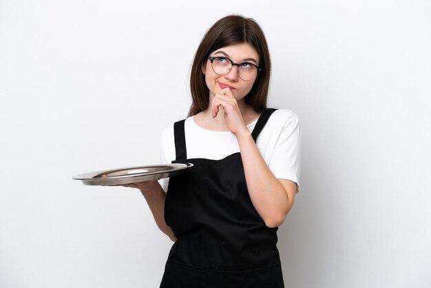 Giovane chef donna russa con vassoio isolato su sfondo bianco e alzando lo sguardo