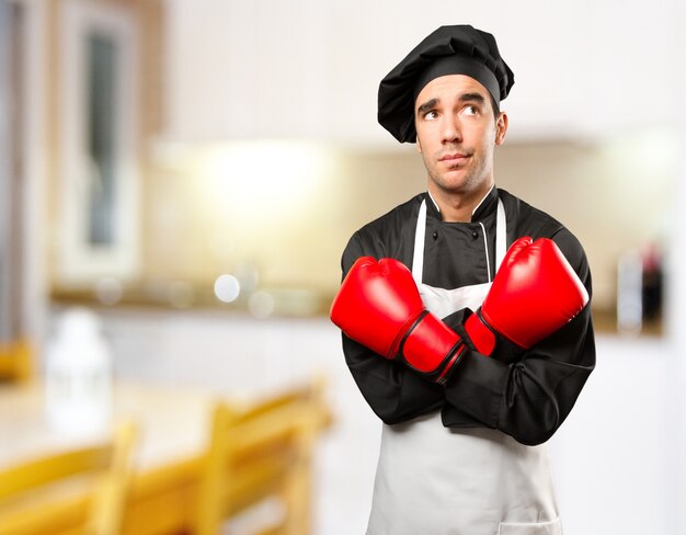 Giovane chef stressato utilizzando un guantone da boxe