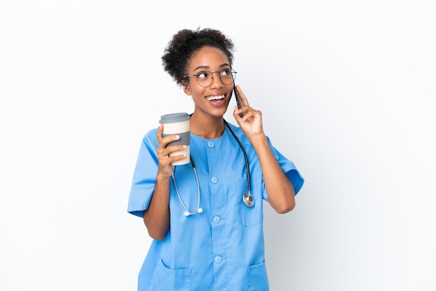 Giovane chirurgo afroamericano medico donna isolata su sfondo bianco tenendo il caffè da asporto e un mobile
