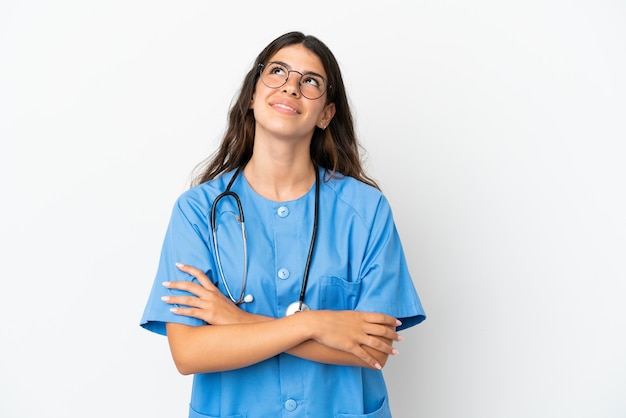 Giovane chirurgo medico donna caucasica isolata su sfondo bianco alzando lo sguardo mentre sorride