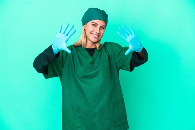 Giovane chirurgo uruguaiano donna in uniforme verde isolata su sfondo blu contando dieci con le dita