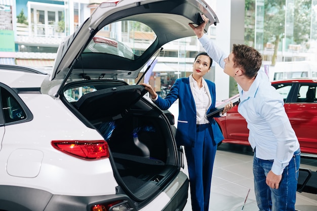 Giovane cliente che controlla la serratura del bagagliaio dell'auto che sta per acquistare