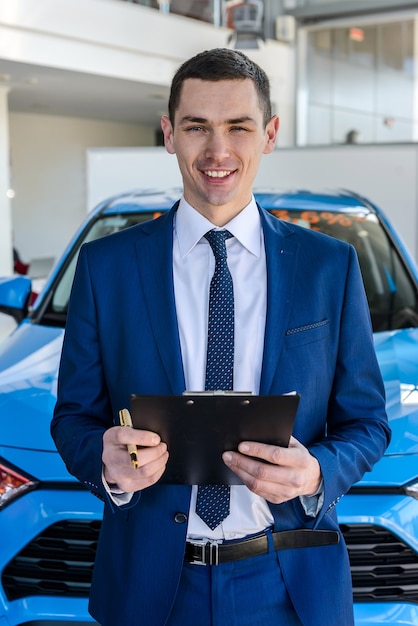 Giovane commerciante di auto che tiene appunti in salone