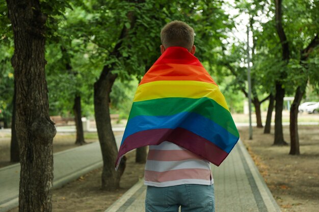 Giovane con bandiera LGBT in piedi all'aperto