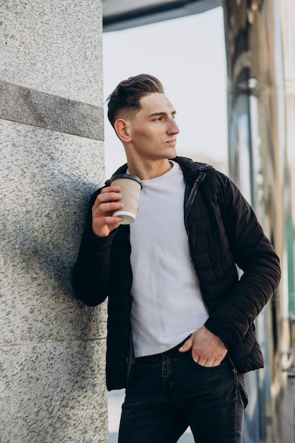 Giovane con caffè che cammina per strada