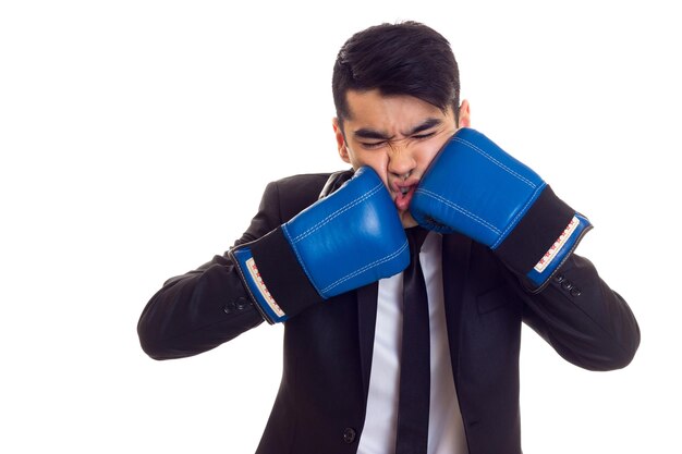 Giovane con capelli neri in camicia bianca e smoking nero con cravatta e guantoni da boxe blu