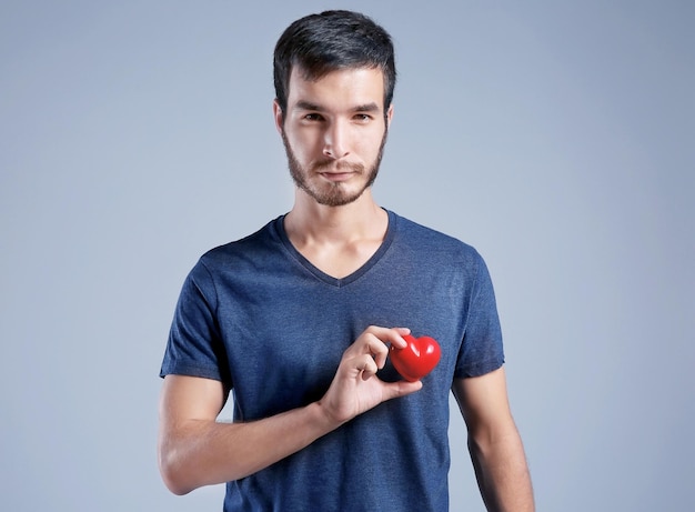 Giovane con cuore rosso su sfondo grigio