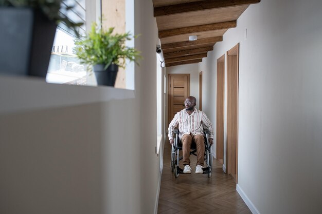 Giovane con disabilità che si muove lungo il corridoio mentre è seduto su una sedia a rotelle