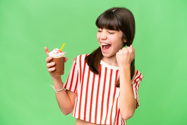 Giovane con frullato al cioccolato su sfondo isolato che celebra una vittoria