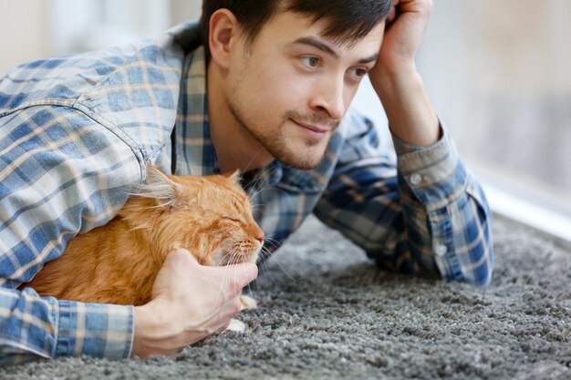 Giovane con gatto birichino sdraiato su un tappeto