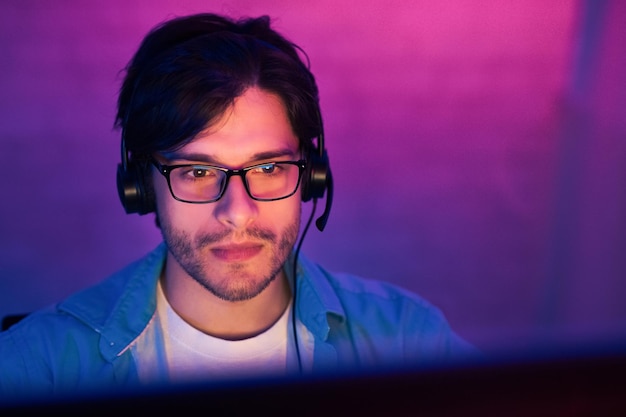 Giovane con gli occhiali e le cuffie che guarda il computer