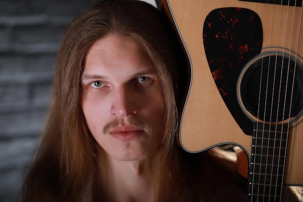 Giovane con i capelli lunghi con una chitarra acustica