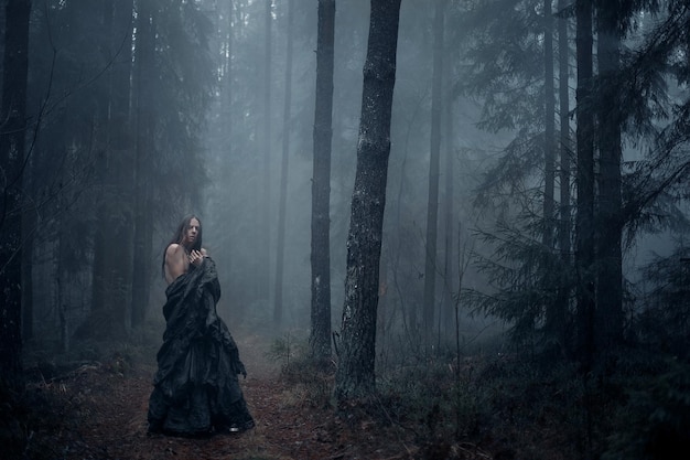 giovane con i capelli lunghi nella foresta oscura