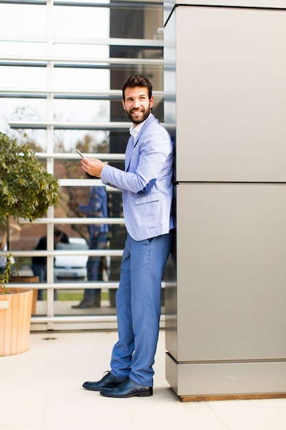 Giovane con il telefono cellulare dall&#39;edificio per uffici