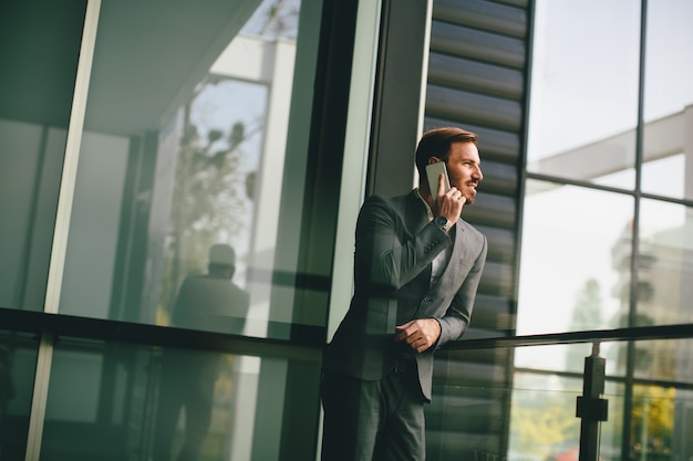 Giovane con il telefono cellulare dall&#39;edificio per uffici