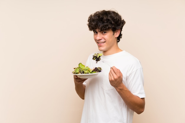 Giovane con insalata sopra la parete verde isolata