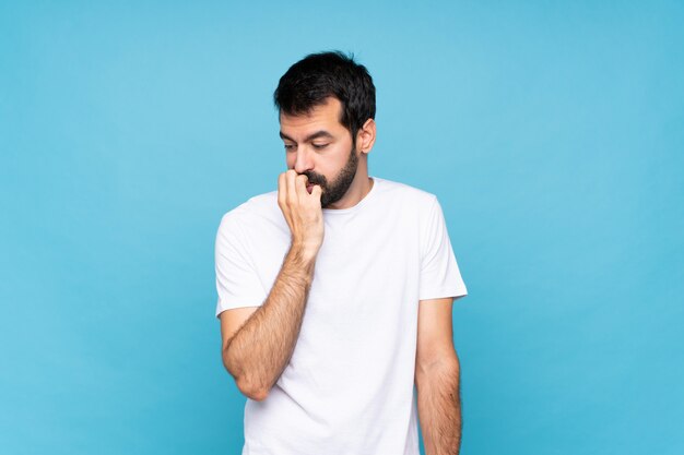 Giovane con la barba sopra il blu isolato che ha dubbi