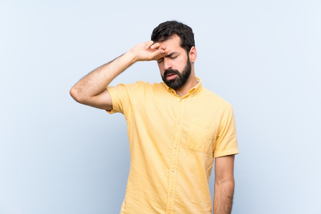 Giovane con la barba sopra il blu isolato con espressione stanca e malata