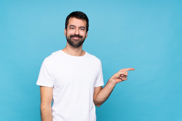 Giovane con la barba sopra il dito indicante blu isolato al lato