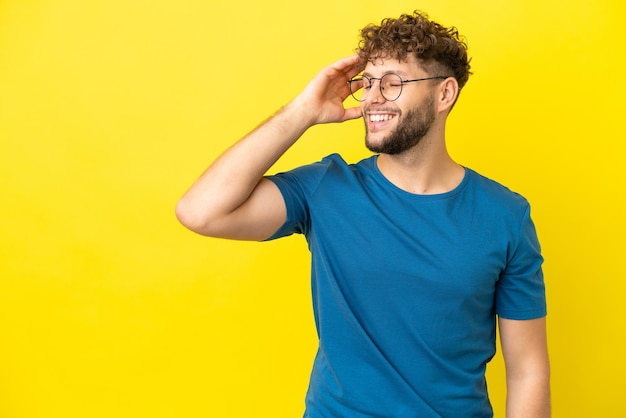 Giovane con la barba su sfondo blu isolato che tiene copyspace immaginario sul palmo per inserire un annuncio