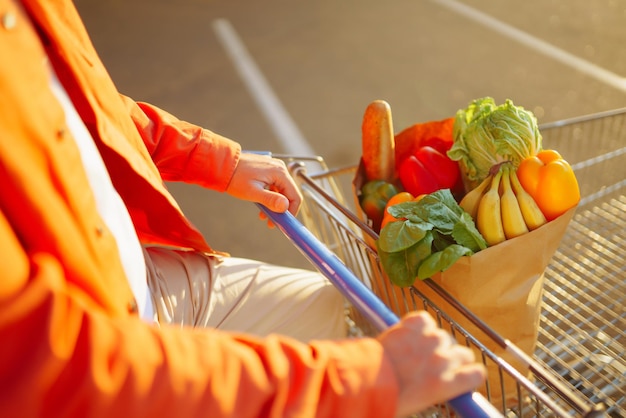 Giovane con la borsa della spesa piena di verdure vicino all'auto Stile di vita sano