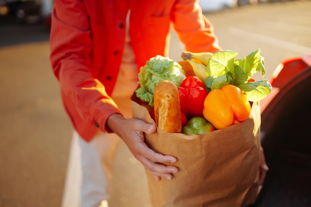 Giovane con la borsa della spesa piena di verdure vicino all'auto Stile di vita sano