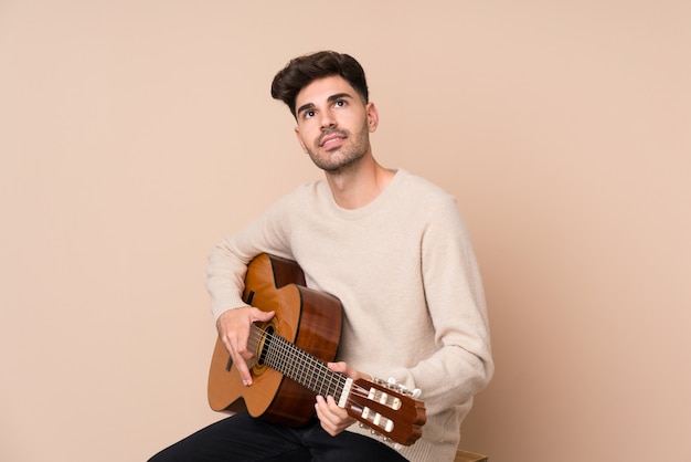 Giovane con la chitarra che osserva in su mentre sorridendo