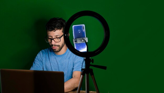 Giovane con laptop che crea video blog Contenuti per creatore di giovani con celphone