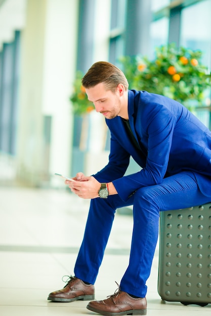 Giovane con lo Smart Phone in aeroporto. Uomo caucasico con il cellulare all'aeroporto mentre aspettando l'imbarco