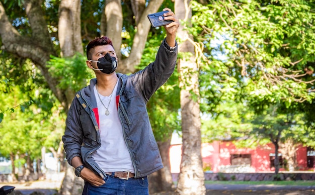 Giovane con maschera che si fa un selfie, giovane che si fa un selfie, uomo in giacca e maschera che si fa un selfie