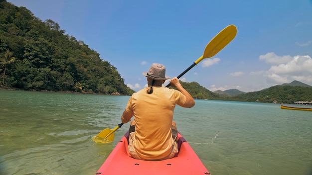 Giovane con occhiali da sole e cappello righe rosa canoa di plastica lungo il mare