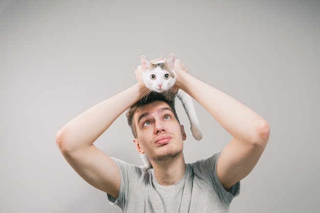 Giovane con simpatico gatto divertente su sfondo chiaro